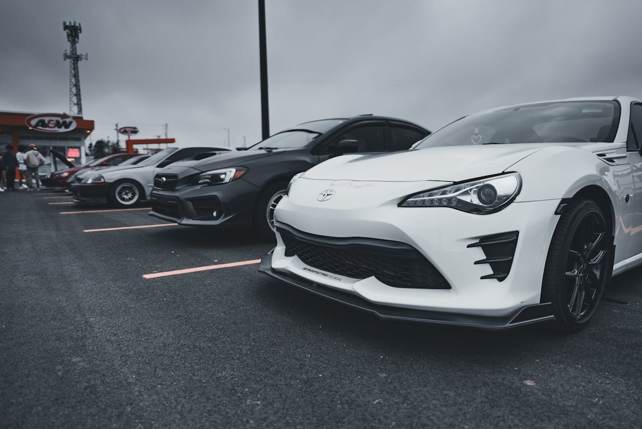 A lineup of stylish sports cars parked outdoors under a cloudy sky.