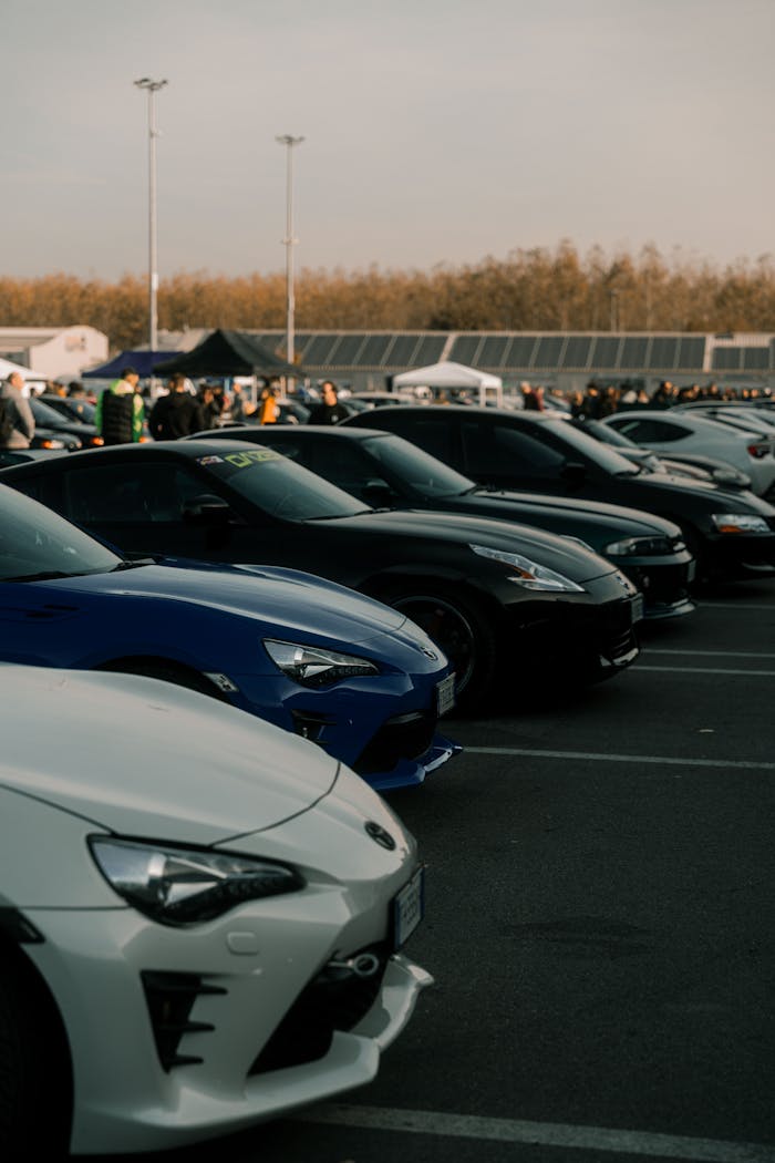 Lineup of sports cars at an outdoor event in Cremona, Italy, showcasing automotive diversity.