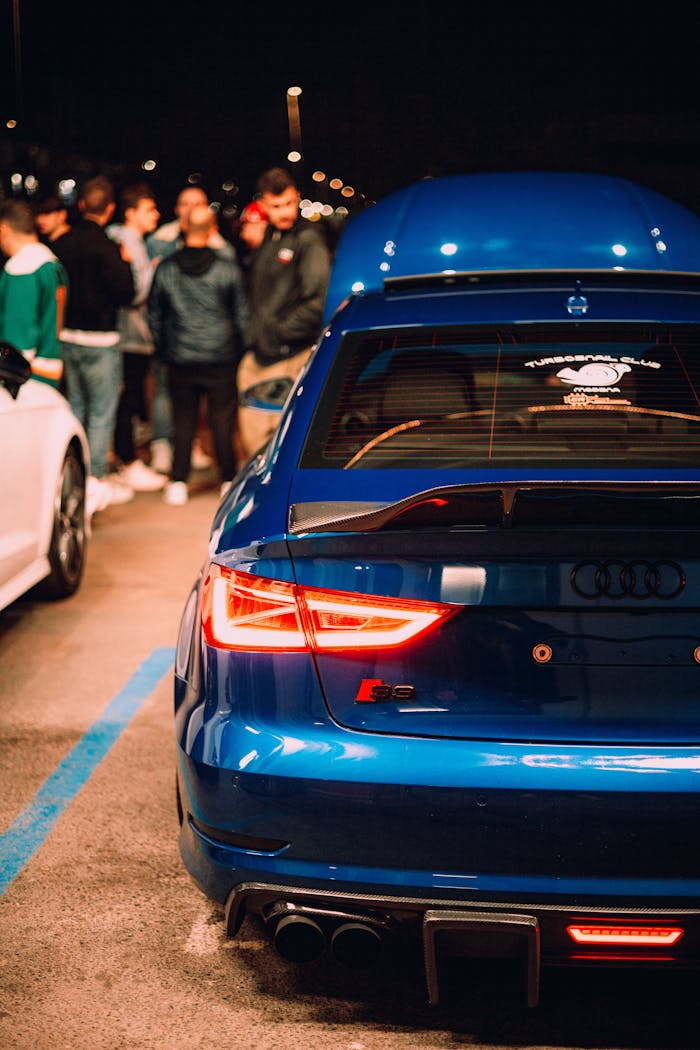 Vibrant nighttime car meet showcasing a blue Audi RS with a group of people.